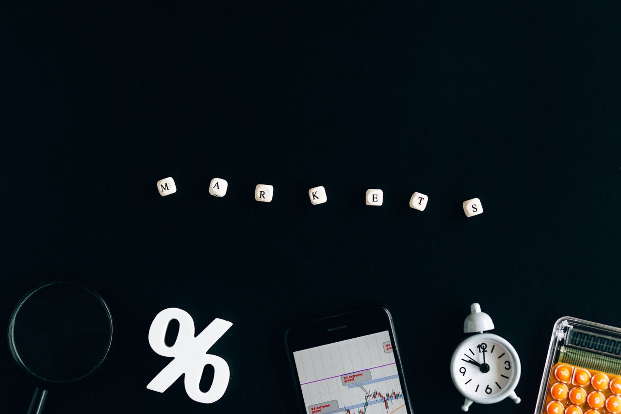 Composition créative illustrant les marchés financiers avec des cubes, des graphiques et une horloge sur fond noir.